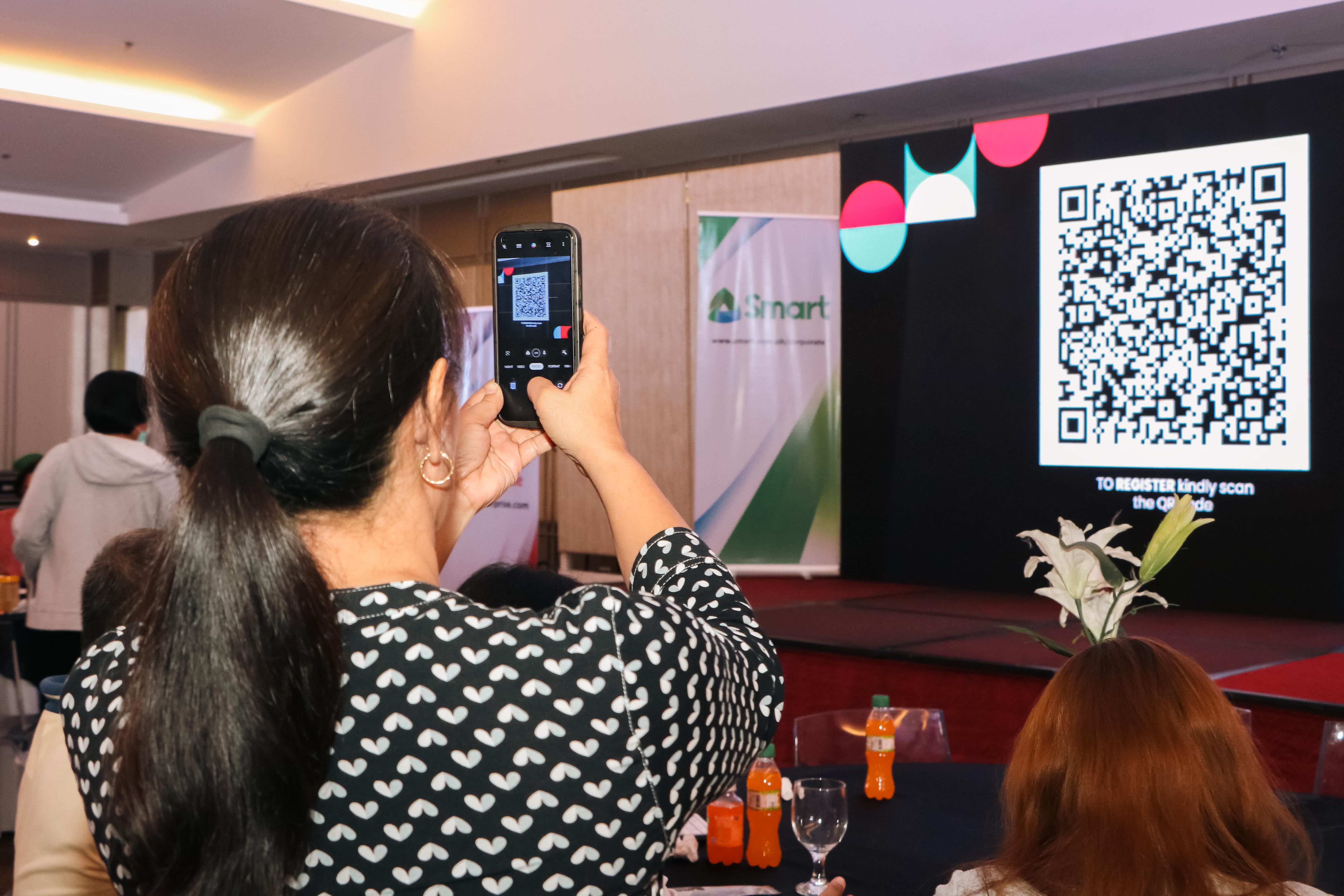 A participant scans the flashed QR code for registration using her smartphone, exhibiting her basic know-how on digital technology.