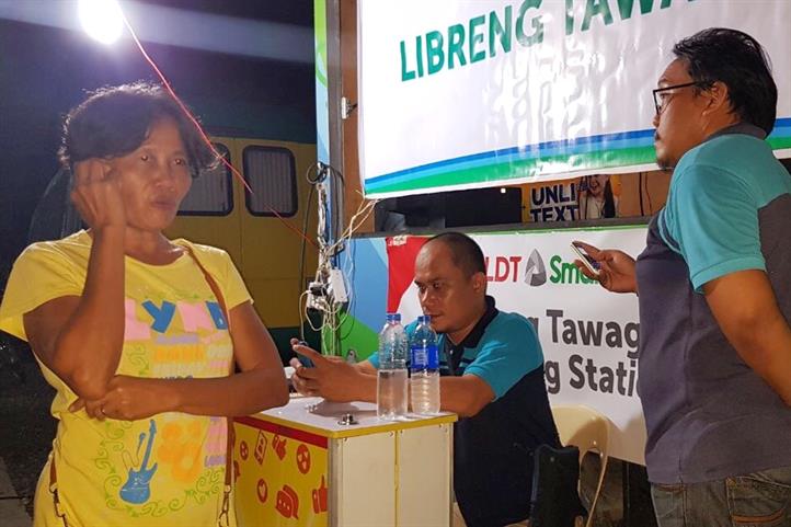A resident makes a phone call at the Smart Libreng Tawag service at Enan Chiong Activity Center. Smart provides communications, relief aid to Cebu landslide survivors