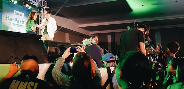 Actor Carlo Aquino serenades a load seller onstage, to the delight of the audience at the Smart Ka-Partner retailers convention in Davao City. Davao load retailer wins Smart Ka-Partner P1M prize