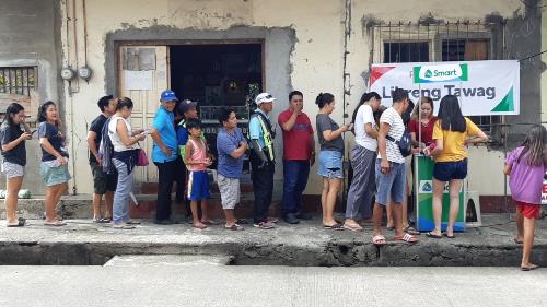 Residents line up at a libreng tawag and charging station in Barangay Rizaliana, Mauban, Quezon. PLDT, Smart provide communication aid for Typhoon ‘Tisoy’ victims