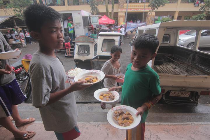 These children hold plates of hot meals during the Tulong Kapatid relief drive at Ligao City Technical and Vocational High School, which has been turned into an evacuation center due to the eruption of Mt. Mayon. Smart joins Mayon relief operations